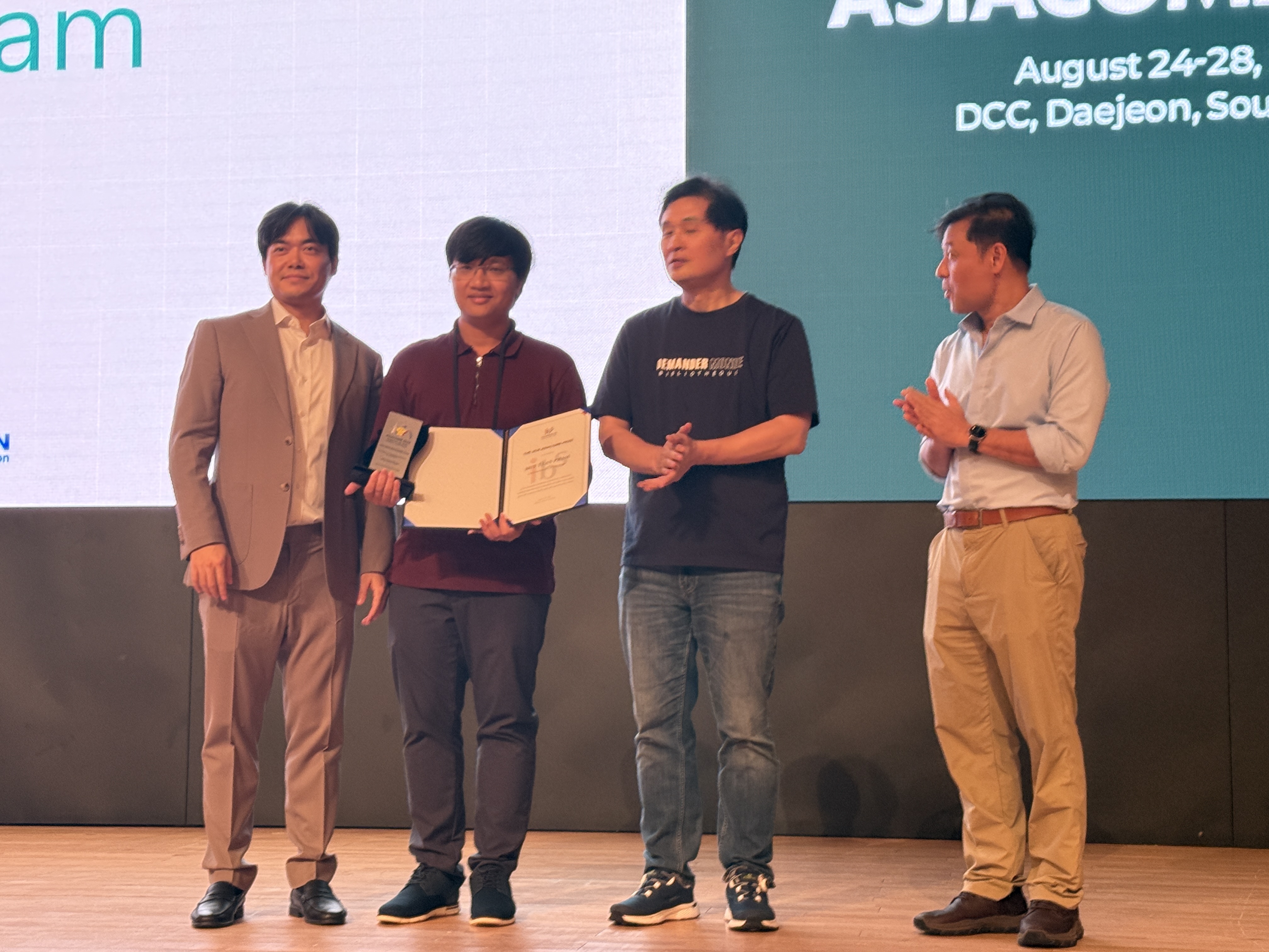 Huy Tuan Pham holding the 2026 ASIACOMB Prize certificate and plaque during the prize ceremony